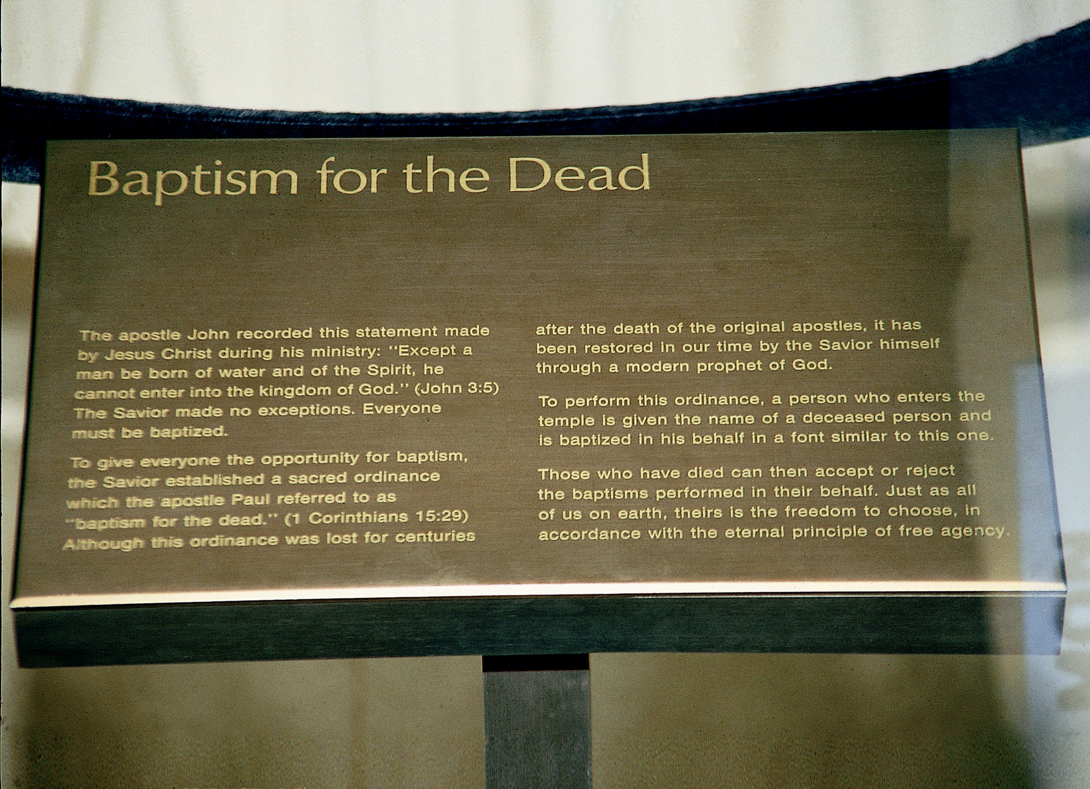 Placard explaining the temple baptismal font above. The second paragraph includes this caption: "... to give everyone an opportunity for baptism, the Savior established a sacred ordinance which the apostle Paul referred to as 'baptism for the dead' (1 Cor